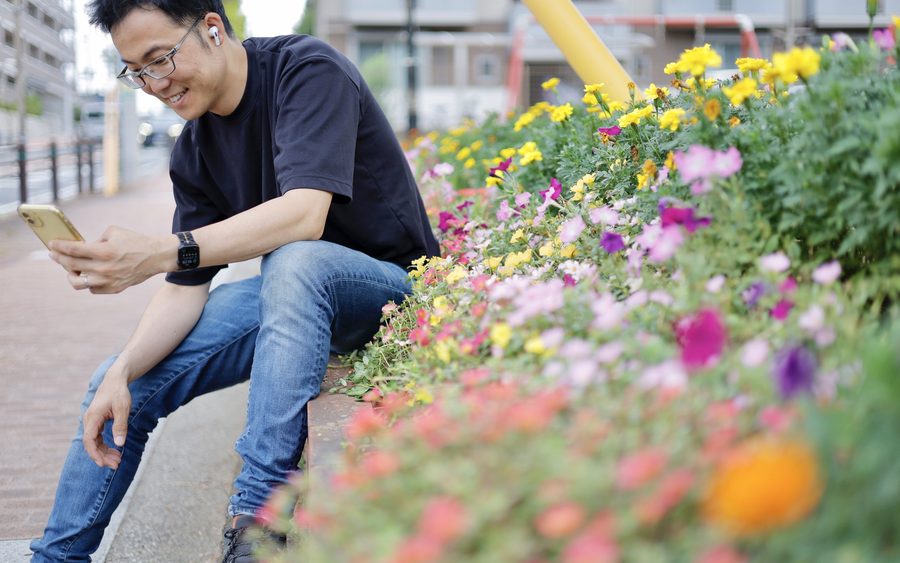 花壇の前でスマートフォンを操作する様子